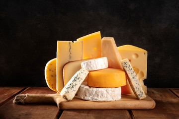 Cheese variety, many different types of cheeses, a side view on a dark background