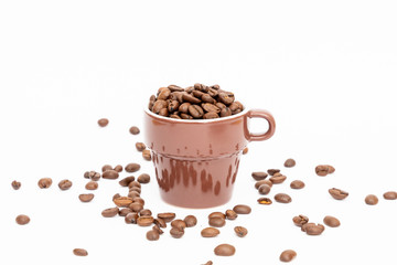 Espresso cup in brown filled with dark coffee beans on white background