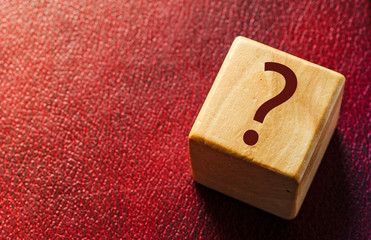 Wooden cube with question mark on red leather