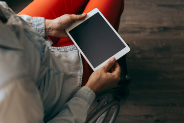 unrecognizable young disabled woman in a wheelchair with a modern tablet.