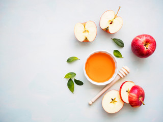 Rote halbierte Äpfel und eine weiße Schüssel mit Honig auf einem hellgrünen Hintergrund, Flat lay, gesunde Ernärhung