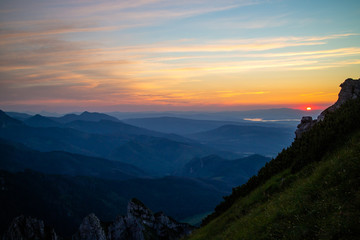 Fototapeta premium Blue silhouettes of Carpathian rocky mountains and sunset orange-blue sky with clouds