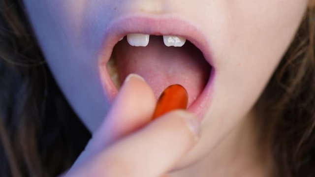 Close up of a sick girl taking her medicine to recover from illness or coronavirus