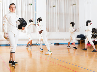 Woman in fencing uniform in gym