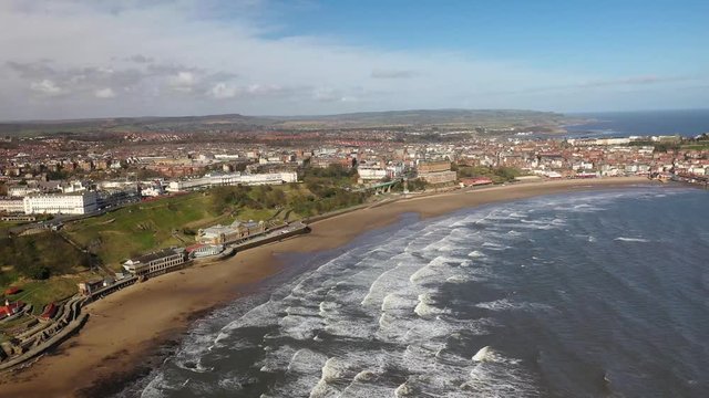 Aerial footage of the British seaside town of Scarborough, the seaside coastal town is located in East Yorkshire in the North Sea coast showing the beach and ocean.