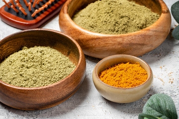 Ayurvedic hair care products. Henna, turmeric and neem powder in bowls on a grey background. Natural care and hair coloring.	