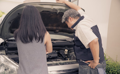 Auto mechanic Check the engine to find the cause. By the woman who owns the car standing