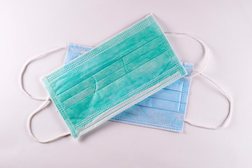 Two surgical breathing masks green and blue top view on white background