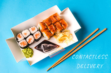 Sushi and rolls in a plastic box and text contactless delivery. Delivery of the product during quarantine. 