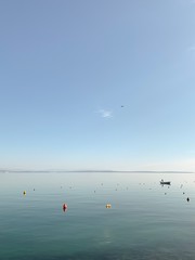 Obraz premium Blue sea and sky background, silhouette of lonely boat