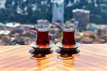 Two cups (armudas) of traditional Turkish tea are served on a table against the background of the Istanbul cityscape