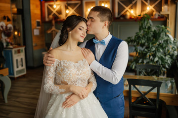 Naklejka premium The groom hugs the bride by the shoulders and kisses her forehead. Love, wedding concept. Happy newlywed couple.
