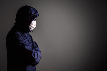 Dark tone of man in hood jacket and virus protective mask