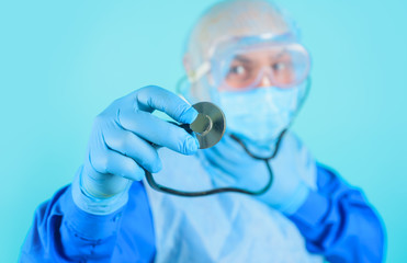 Healthcare and medicine concept. Doctor with stethoscope in hand. Selective focus. Diagnostic instrument, hospital equipment. Advertising hospital, clinic. Doctor in protective suit and medical mask.