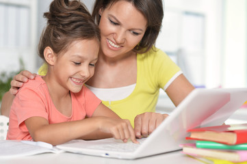 Close up portrait of happy mother and daughter using laptop together
