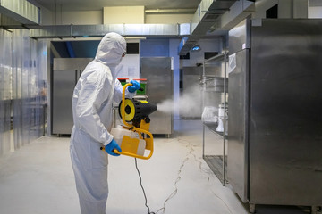 man in protective equipment disinfects with a spray gun surfaces due to coronavirus covid-19 .Virus...