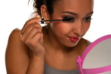Young dark skinned woman applying a mascara