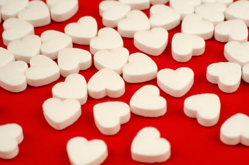 Fototapeta na wymiar white plastic bottle and scattered white pills on red table.
