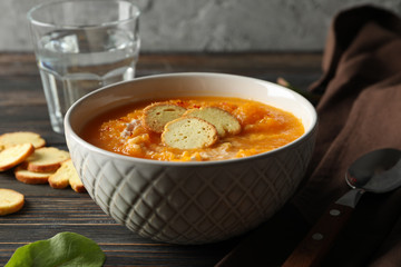 Pumpkin cream soup with croutons on wooden background, close up