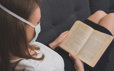 Naklejka premium Woman in medical mask reading book. Isolation at home.