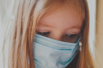 Closeup portrait of a little girl in a medical mask. home quarantine 
