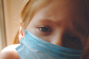 Closeup portrait of a little girl in a medical mask. home quarantine 