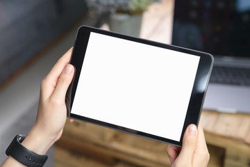 Close-up of hand holding black tablet on sofa in living room.