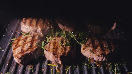 Delicious juicy meat steak cooking on grill. Aged prime rare roast grilling tenderloin fresh marble tenderness beef. Prime beef fry on electric roaster, rosemary, black pepper, salt. Slow motion.