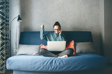 A girl works from home or a student is studying from home or a freelancer. She uses a laptop and a phone.