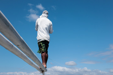 Man standing on a bamboo pole against a clear blue sky