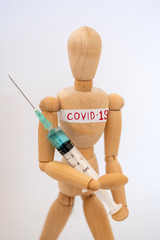 COVID-19 Pandemic Coronavirus concept ; Close-up of a wooden model man is carrying syringe. Corona virus vaccine on the way.
