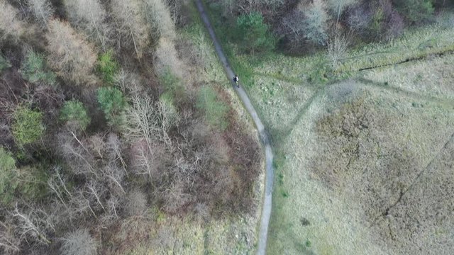Aerial view of a cyclist riding a mountain bike through rural woodland in south wales