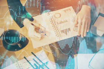 Multi exposure of hands making notes with forex chart huds. Stock market concept.