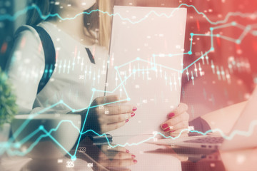 Double exposure of hands making notes with forex chart huds. Stock market concept.