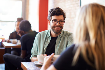 Couple Meeting And Chatting In Coffee Shop Sitting At Table