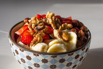 Healthy breakfast. Fresh porridge, with strawberry, banana and nuts in a bowl on white background. Macro.