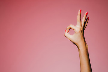 Woman's hands with bright manicure isolated on pink background okay super gesture