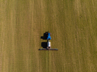 Tractor applying liquid mineral fertilizers to the soil on winter wheat