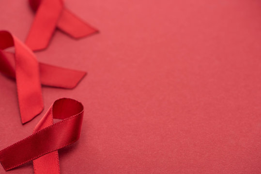 selective focus of red awareness aids ribbons on red background with copy space