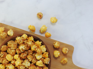 Top view of delicious popcorn in round wooden plate isolated on gray marble background. Include buttery caramel corn and rich cheddar cheese corn. Food and snack concept. With copy space.
