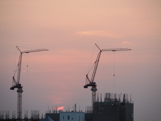 Silhouette tower crane in building construction site on Sunset Background.