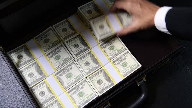 A hand packing of 100 dollar bills in a briefcase .