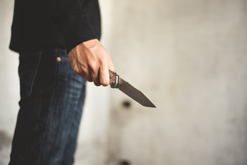 Close up of man holding knife in abandoned house. Terrorist and Robber concept. Police and Soldier. Weapon and armed theme - obrazy, fototapety, plakaty