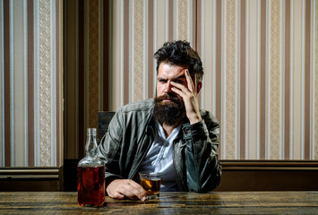 Fototapeta premium Bearded brutal hipster man drinking expensive cognac. Serious problems with alcohol addiction. Alcoholism treatment. Handsome man drinking alone.