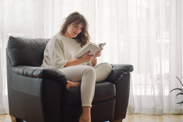 Beauty young woman is reading a book at home. Thoughtful girl reading important book