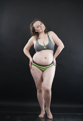 plus size woman shows her body in stretch marks and hair with cellulite and encourages you to love and accept yourself in any way . black background in the Studio. full- length photo.