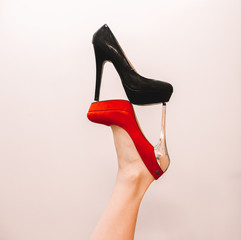 fashionable background for advertising shoes, red and black shoes on the foot in an unusual interesting position with a white background