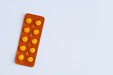 Pills in a yellow blister on white background close-up. View from above.