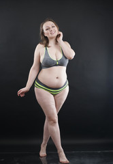 plus size woman shows her body in stretch marks and hair with cellulite and encourages you to love and accept yourself in any way . black background in the Studio. full- length photo.