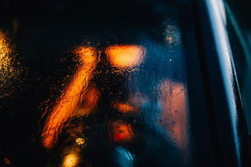 Person unfocused through the window car with drops